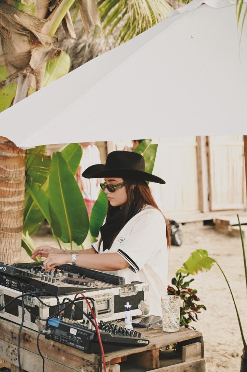 MARA con sombrero y lentes en cabina de playa, portada de su mediakit